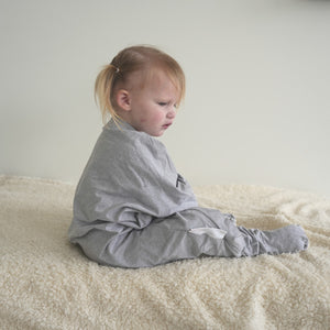 Toddler in gray onesie pajamas with opening feet and hand covers