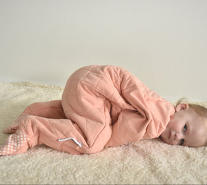 Sleepy toddler wearing a dusty pink quilted toddler onesie for Winter sleep