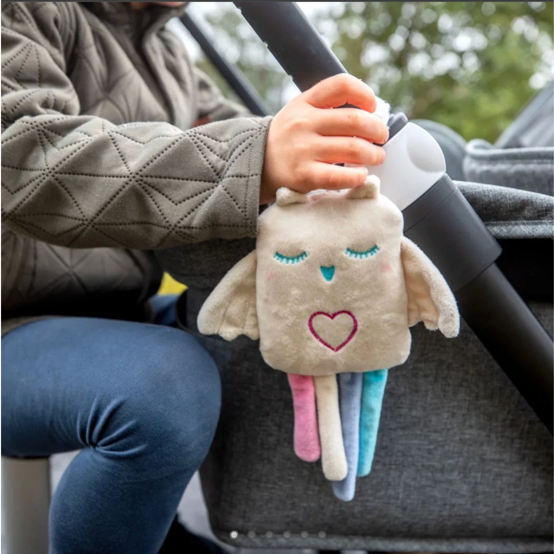 A plush owl baby heartbeat sound accessory strapped to a stroller handle.