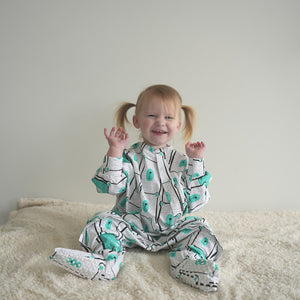 Adorable toddler wearing a mint bear patterned sleep onesie with zipper access for easy diaper changes