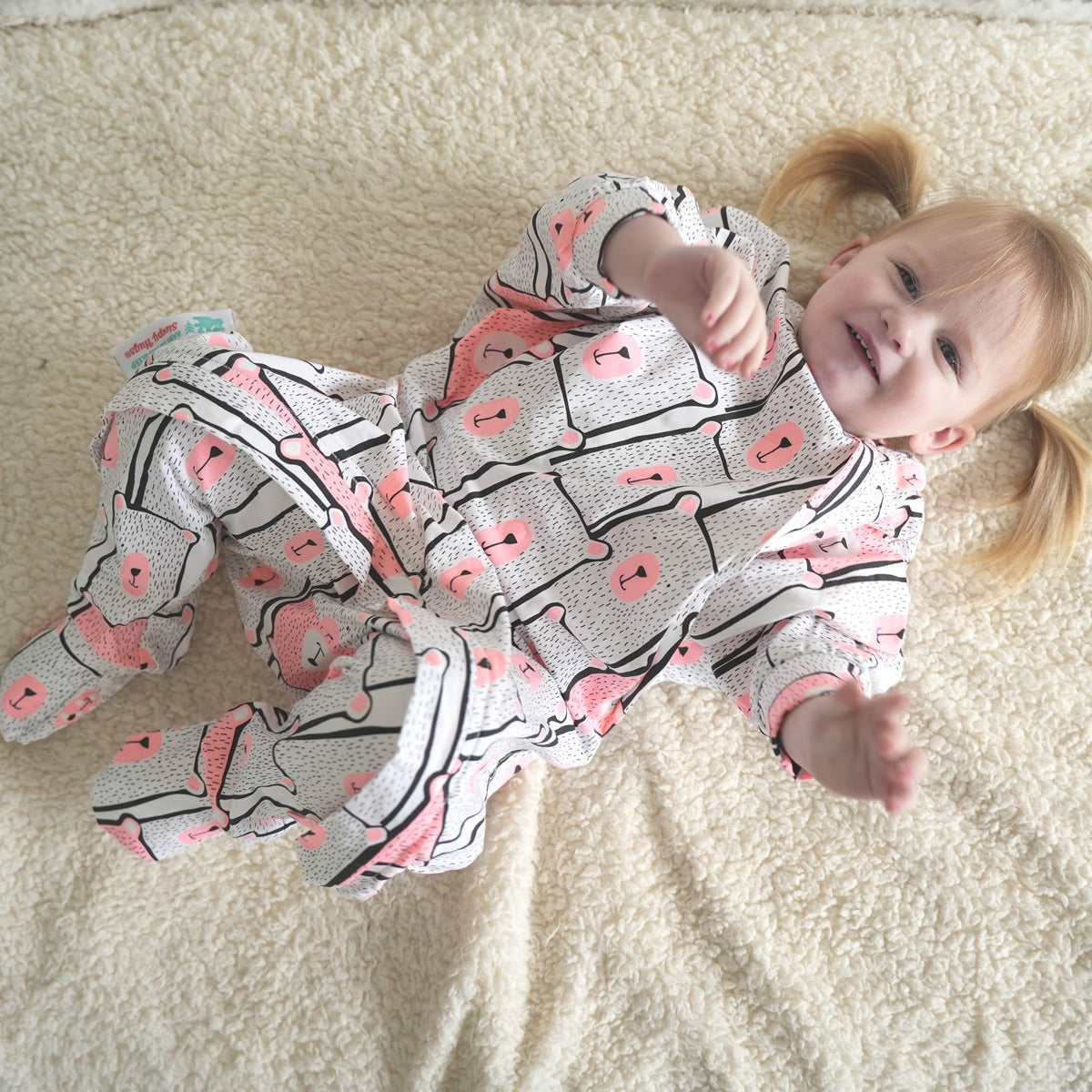 Toddler wearing a pink bear patterned sleep onesie with zipper access for easy diaper changing