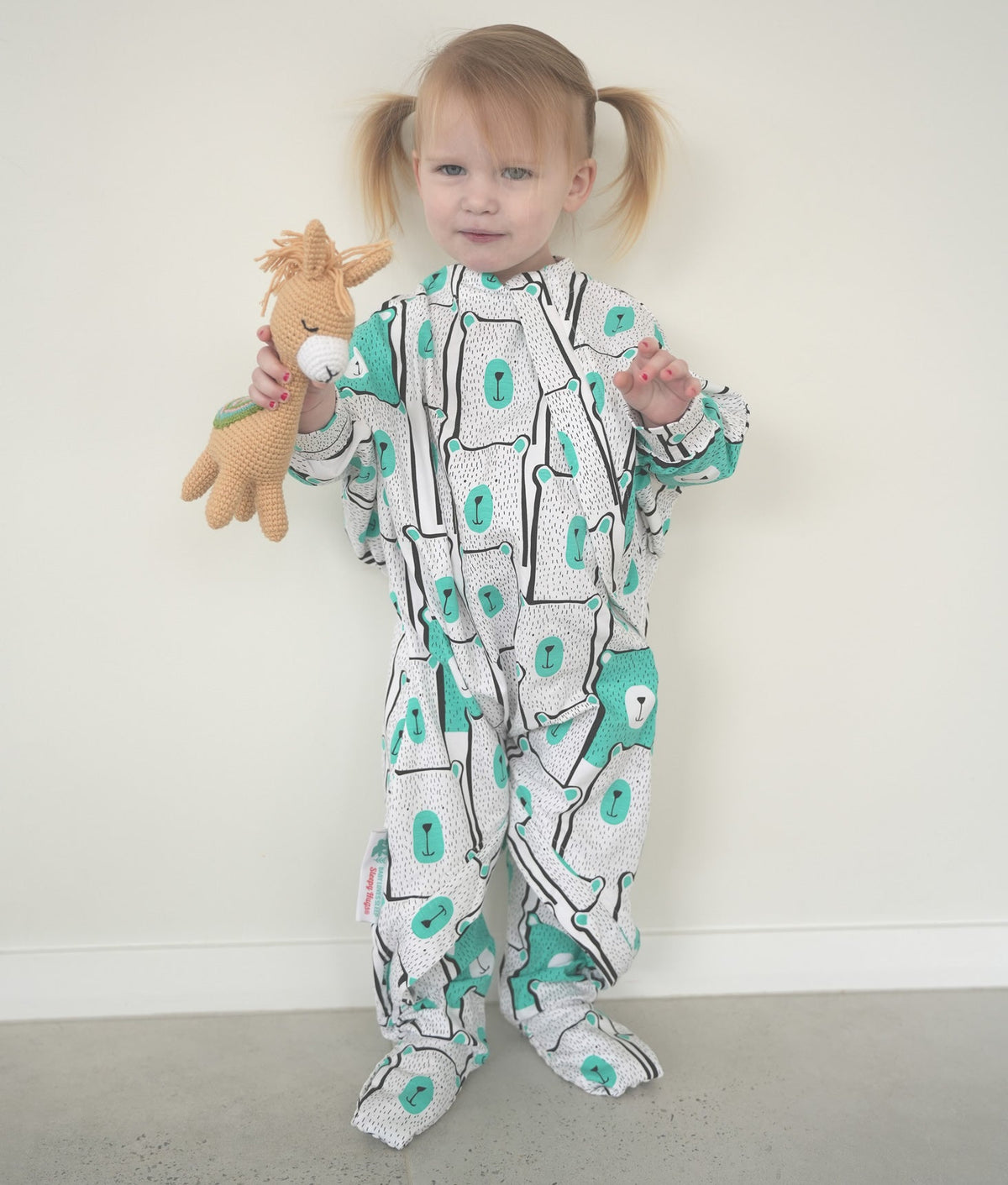 Toddler wearing a patterned onesie with feet and hand covers