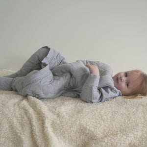 Toddler in a gray quilted sleep onesie with zipper access for easy diaper changing
