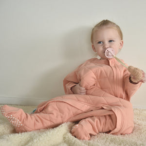 Toddler wearing a dusty pink sleep onesie suit with zipper access for easy diaper changing